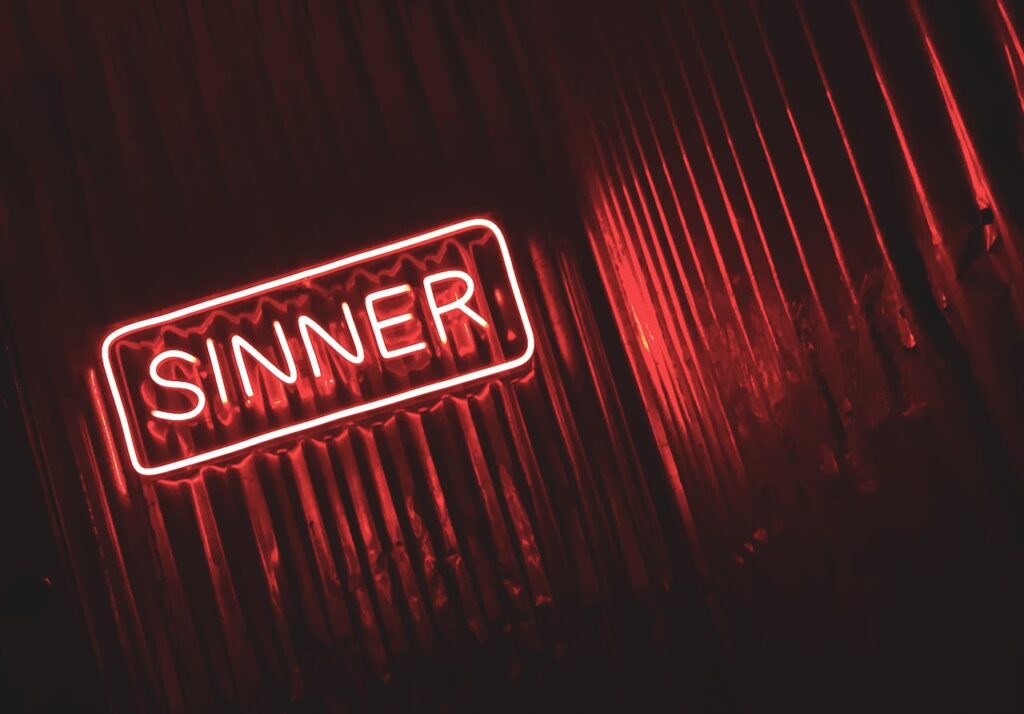 Demo Post 1 Bright red neon sign displaying the word 'SINNER' against a dark, moody background.